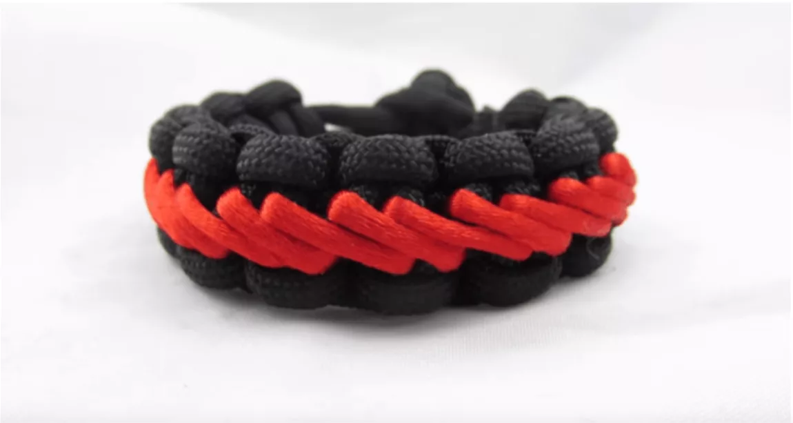 Screenshot 20260708 at 123816 AM Explore Magazine Braided paracord bracelet in black with a red stripe on a white background