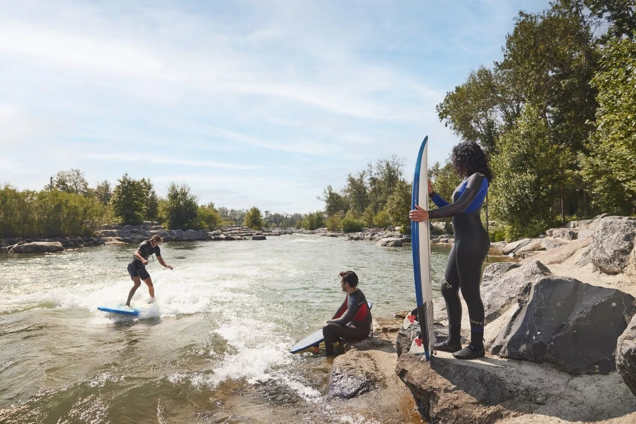 Three people surfing on a river in Calgary, Alberta.