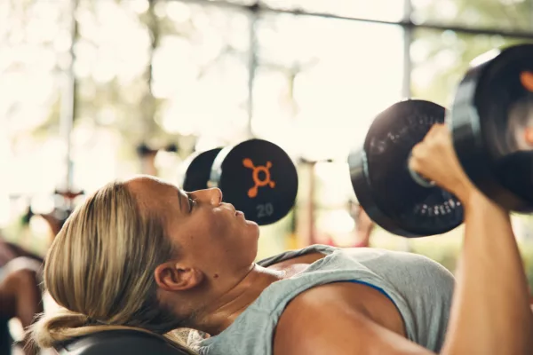 A woman lifts weights at an Orangetheory fitness class