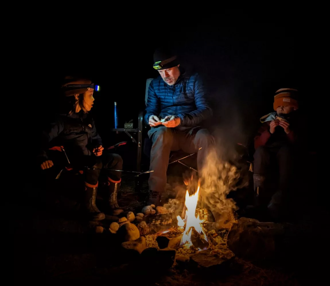 Camping trips with kids - family stays up late around a fire while camping