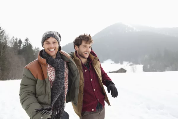 Portrait of happy men walking in snowy field