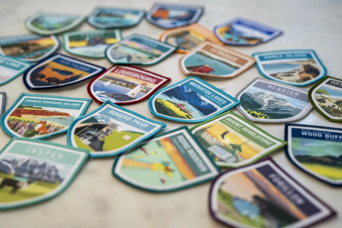 Colorful travel patches scattered on a surface, each featuring a destination image or name (souvenir badges).